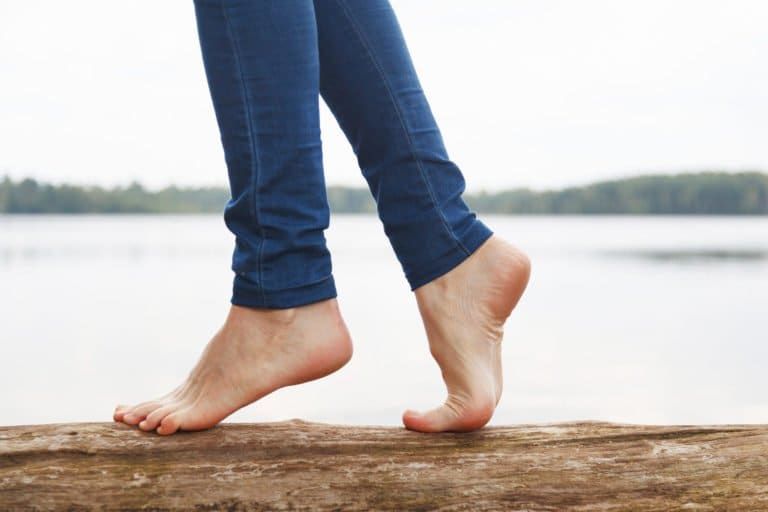 a person's feet on a rock by a body of water